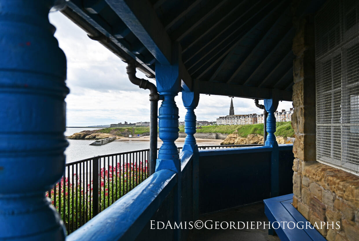 Geordie Photographs 1 A view south of Cullercoats Bay, the headland, Beverley Terrace and St George's spire framed by the blue veranda of the Watch House
